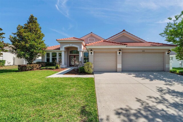 mediterranean / spanish-style home featuring a tiled roof, driveway, a front yard, an attached garage, and stucco siding