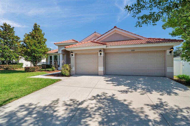 mediterranean / spanish-style home with a garage, a front lawn, stucco siding, and concrete driveway