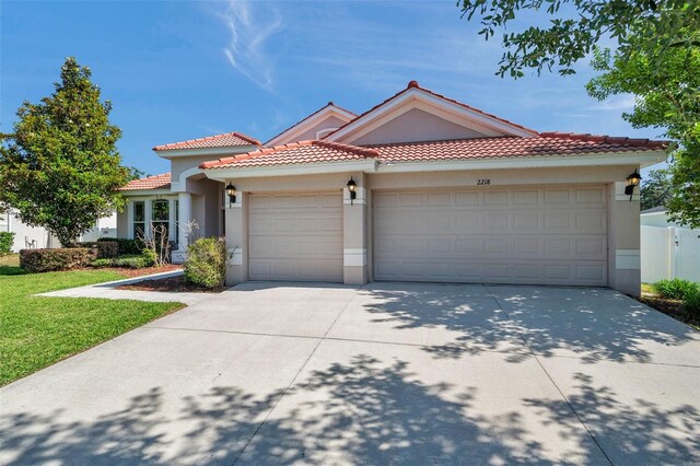 mediterranean / spanish house with a garage, stucco siding, concrete driveway, and a tile roof