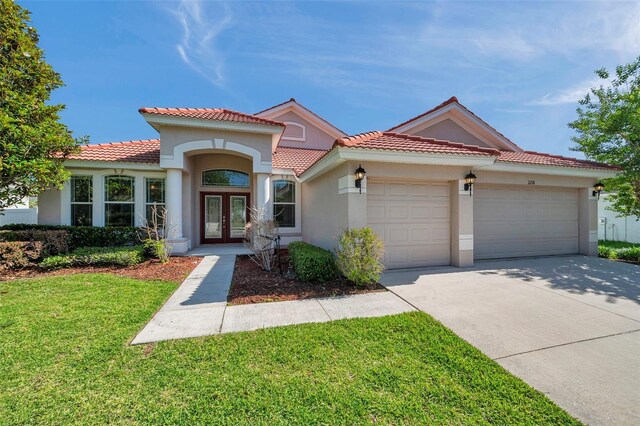 mediterranean / spanish-style home with stucco siding, french doors, a tiled roof, concrete driveway, and an attached garage