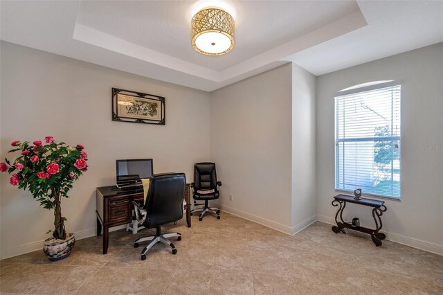 office area featuring a tray ceiling and baseboards