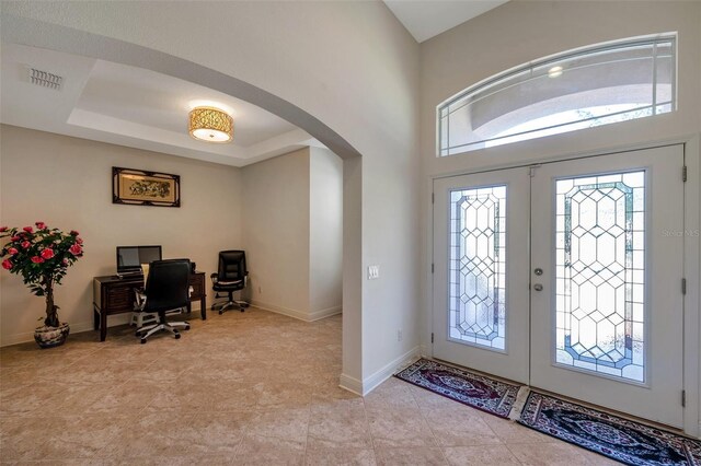 foyer entrance with arched walkways, a wealth of natural light, baseboards, and visible vents