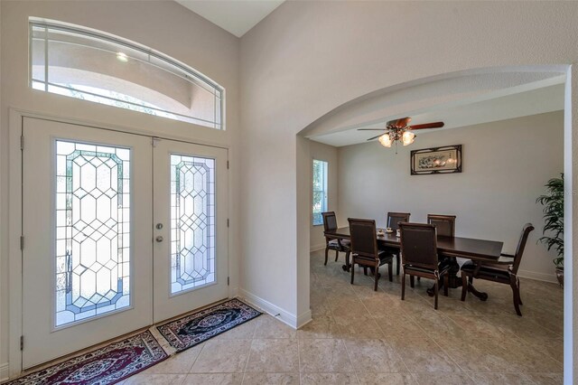 entrance foyer with baseboards, arched walkways, ceiling fan, and light tile patterned floors