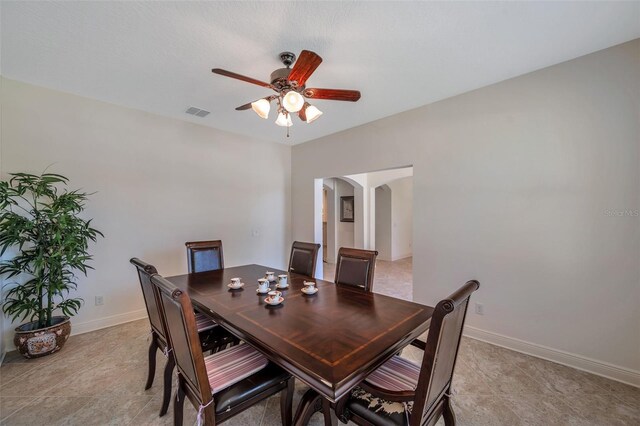 dining area featuring visible vents, a ceiling fan, baseboards, and arched walkways