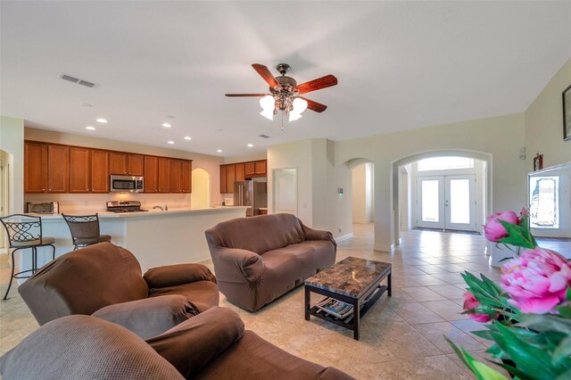 living area with ceiling fan, visible vents, arched walkways, light tile patterned floors, and recessed lighting