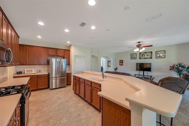 kitchen with visible vents, arched walkways, a sink, a breakfast bar, and stainless steel appliances
