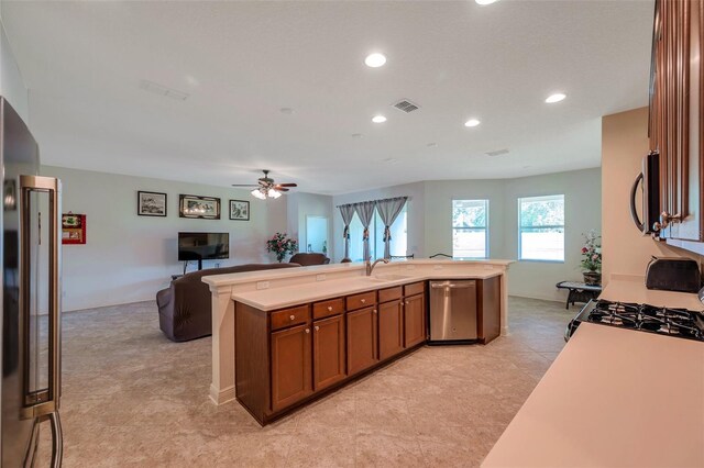 kitchen with light countertops, open floor plan, brown cabinets, and stainless steel appliances