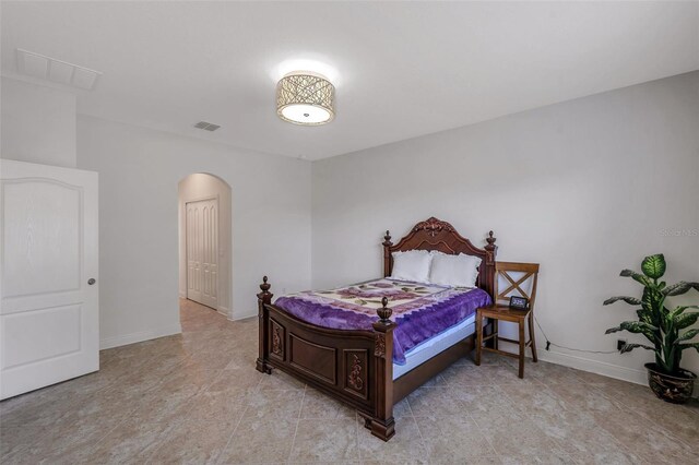 bedroom with visible vents, arched walkways, and baseboards
