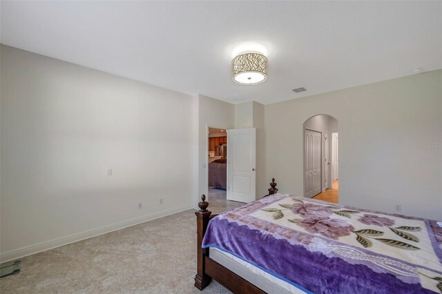 bedroom with arched walkways, baseboards, visible vents, and a closet