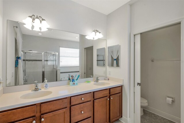 bathroom featuring a sink, a stall shower, toilet, and double vanity