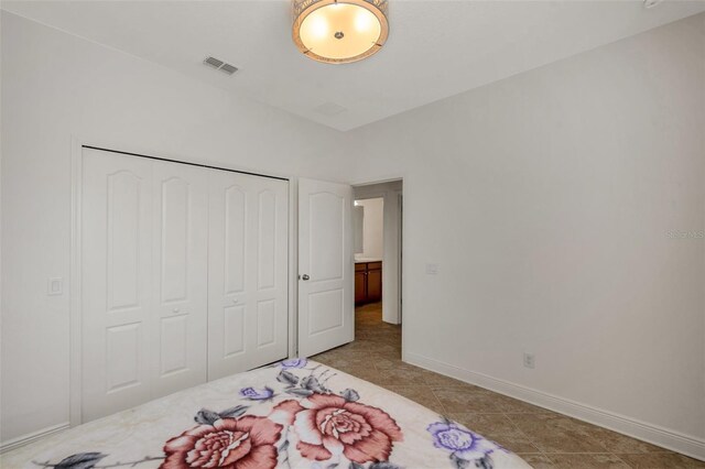 bedroom with light tile patterned floors, baseboards, a closet, and visible vents