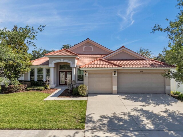 mediterranean / spanish-style house with a garage, stucco siding, french doors, and concrete driveway