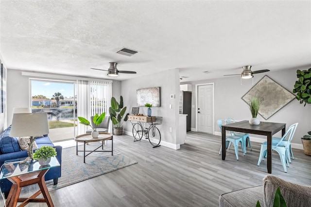 living room with visible vents, a ceiling fan, baseboards, and wood finished floors