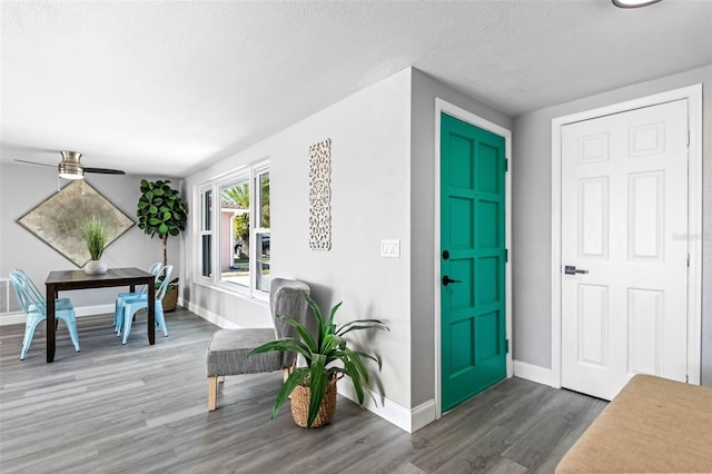 foyer entrance featuring a textured ceiling, baseboards, a ceiling fan, and wood finished floors