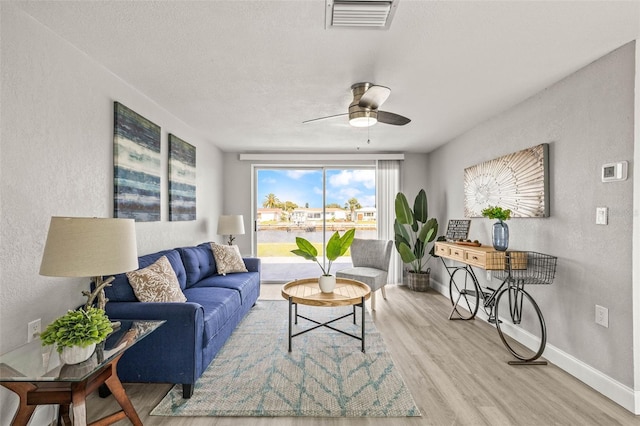 12700 5th Isle, Hudson, FL 34667 - living area featuring a textured wall, light wood finished floors, a ceiling fan, baseboards, and a textured ceiling