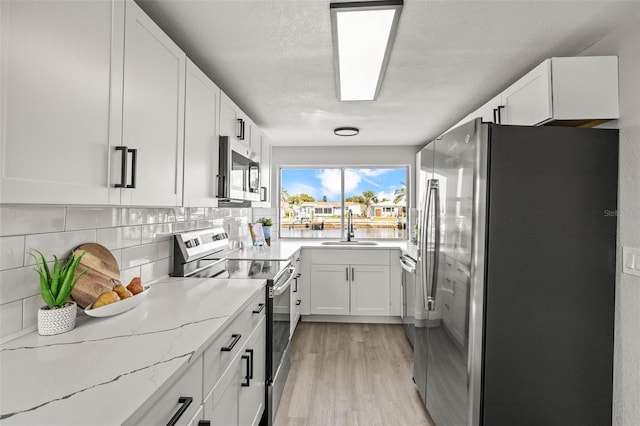 12700 5th Isle, Hudson, FL 34667 - kitchen with appliances with stainless steel finishes, a sink, light wood-type flooring, white cabinetry, and light stone countertops