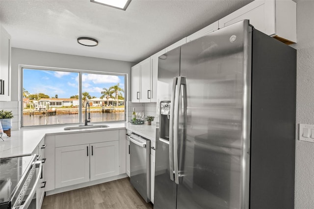 12700 5th Isle, Hudson, FL 34667 - kitchen with appliances with stainless steel finishes, a sink, light wood finished floors, a water view, and white cabinets