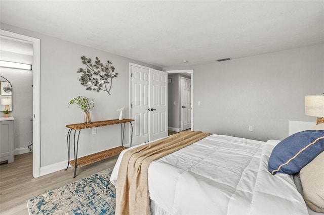 12700 5th Isle, Hudson, FL 34667 - bedroom with light wood finished floors, baseboards, and connected bathroom