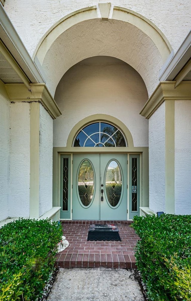 property entrance with covered porch and stucco siding