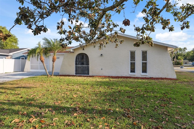 view of front of house with concrete driveway, stucco siding, fence, and a front yard