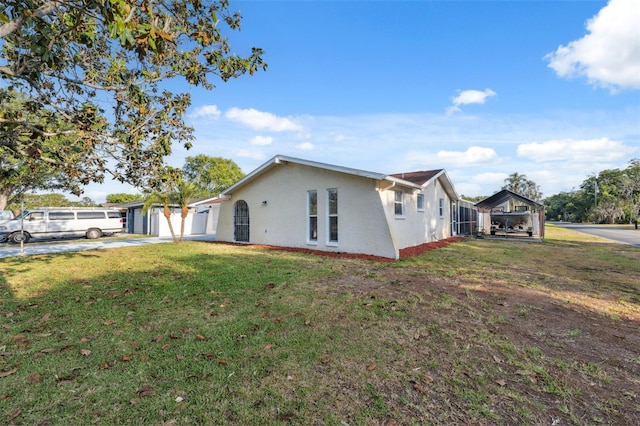 view of home's exterior featuring a lawn, driveway, a detached carport, and stucco siding