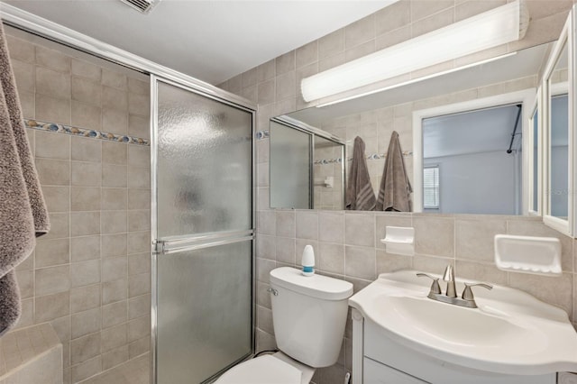 bathroom featuring tile walls, vanity, toilet, and a shower stall
