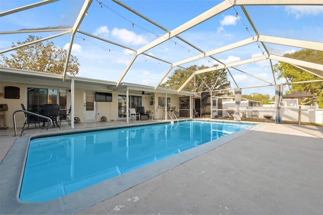 pool with a ceiling fan, a patio area, and glass enclosure