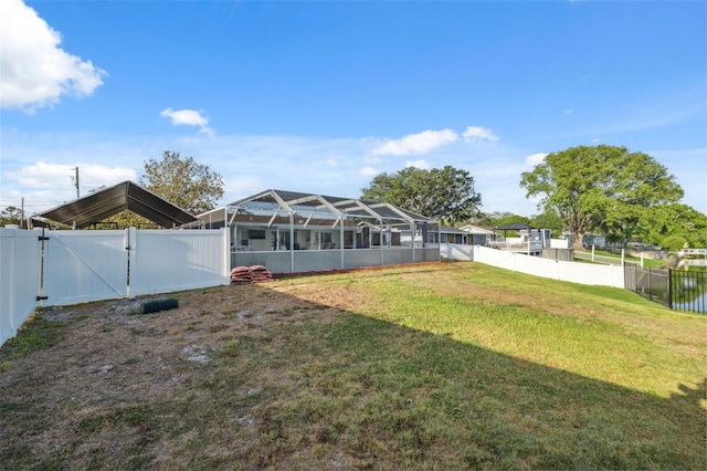 view of yard with a gate, a fenced backyard, and glass enclosure