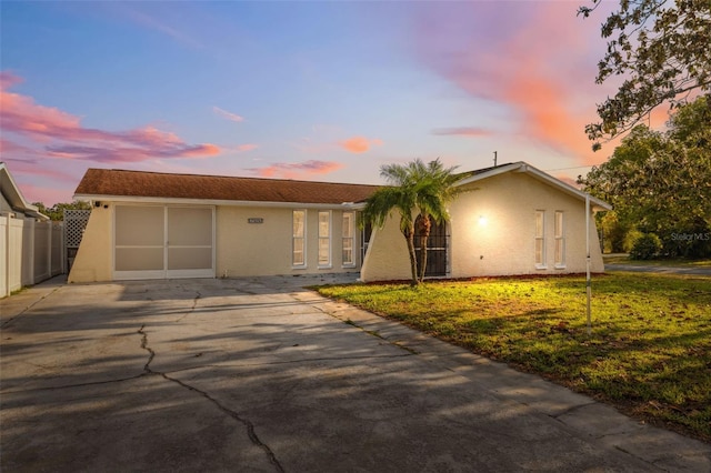 ranch-style home with fence, an attached garage, concrete driveway, stucco siding, and a front yard
