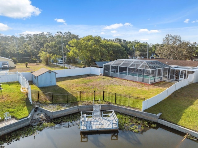 dock area with a fenced backyard, a water view, and a lawn
