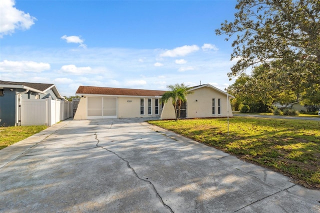 ranch-style house with fence, stucco siding, a front lawn, and driveway