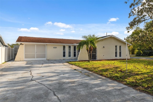 ranch-style home with concrete driveway, stucco siding, fence, and a front yard