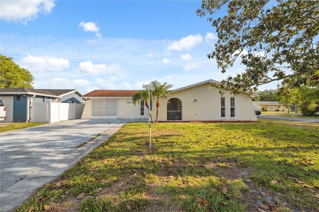 ranch-style house featuring concrete driveway, stucco siding, fence, and a front lawn