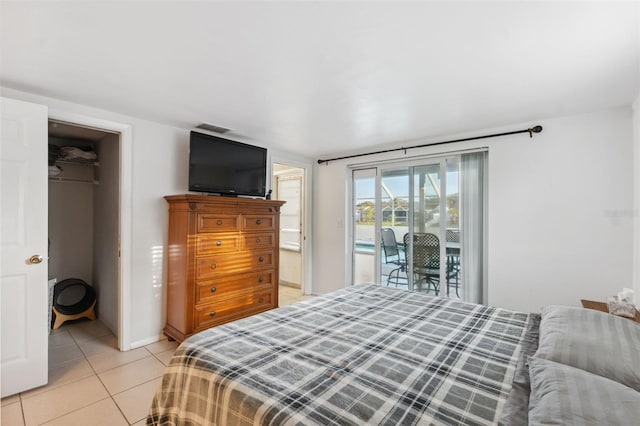 bedroom with a closet, visible vents, a spacious closet, light tile patterned floors, and access to exterior