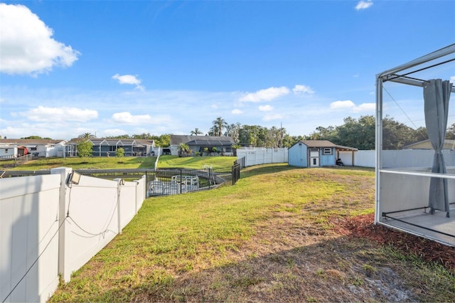 view of yard with an outdoor structure, a residential view, a fenced backyard, and a storage unit