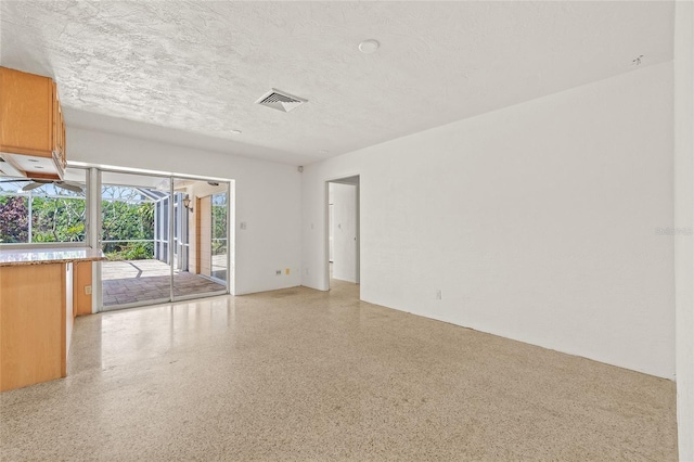 1141 80th Street Ct S, Saint Petersburg, FL 33707 - spare room featuring dark aggregate flooring and a textured ceiling