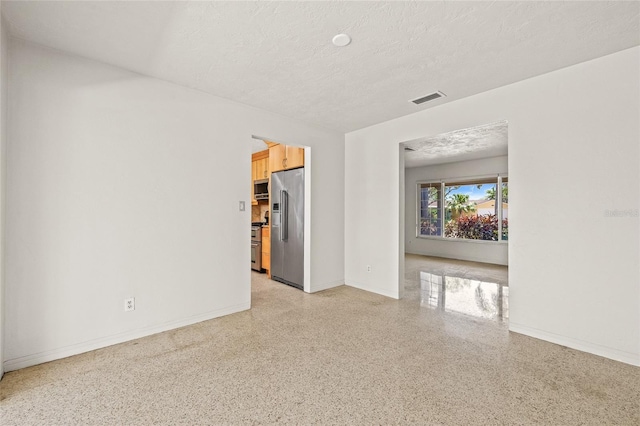1141 80th Street Ct S, Saint Petersburg, FL 33707 - empty room featuring dark speckled floor, a textured ceiling, and baseboards