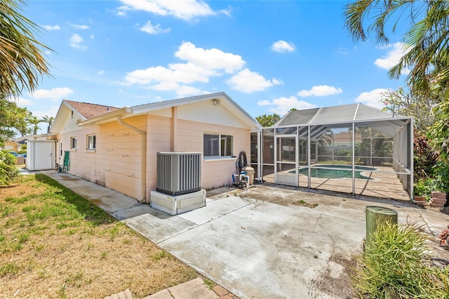 1141 80th Street Ct S, Saint Petersburg, FL 33707 - back of property featuring central AC unit, a patio, an outdoor pool, and glass enclosure