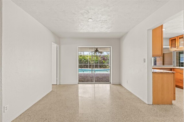 1141 80th Street Ct S, Saint Petersburg, FL 33707 - unfurnished room with a textured ceiling, speckle patterned floor, baseboards, and ceiling fan