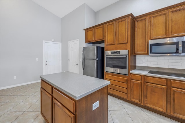 10506 Sky Flower Ct, Land O Lakes, FL 34638 - kitchen with light tile patterned flooring, appliances with stainless steel finishes, brown cabinetry, backsplash, and a kitchen island