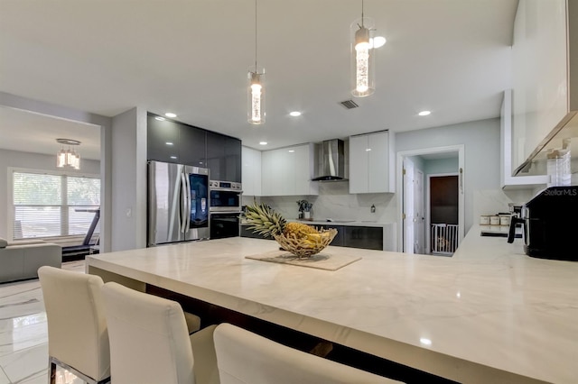 kitchen with hanging light fixtures, wall chimney exhaust hood, stainless steel appliances, a peninsula, and modern cabinets