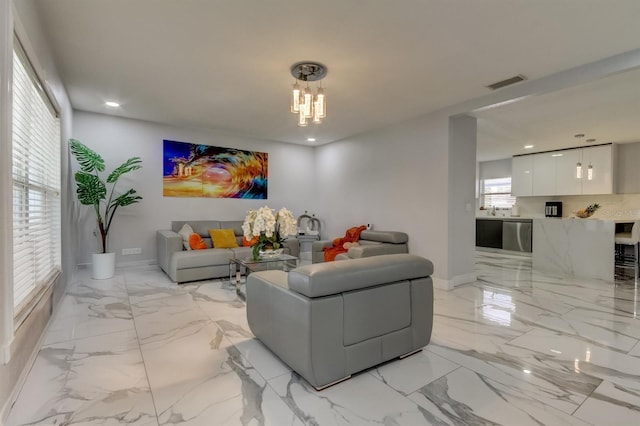living area with baseboards, visible vents, a notable chandelier, and marble finish floor