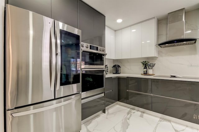 kitchen with appliances with stainless steel finishes, marble finish floor, wall chimney exhaust hood, white cabinetry, and modern cabinets
