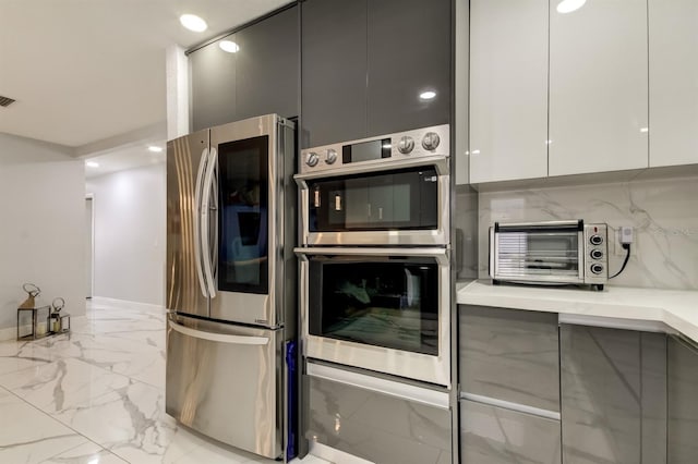 kitchen with marble finish floor, a toaster, modern cabinets, white cabinets, and appliances with stainless steel finishes