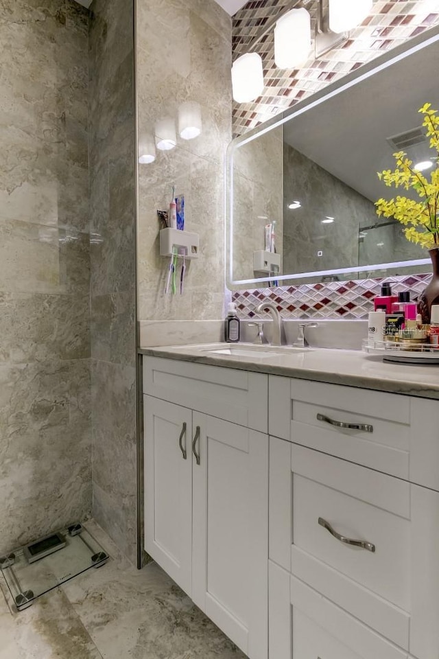 bathroom featuring tile walls, decorative backsplash, marble finish floor, and vanity