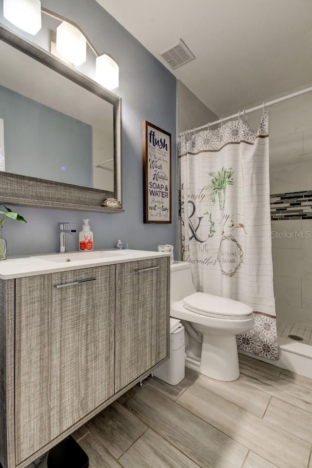full bath with visible vents, vanity, wood finished floors, curtained shower, and toilet