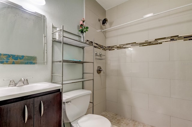 full bath featuring toilet, a tile shower, and vanity