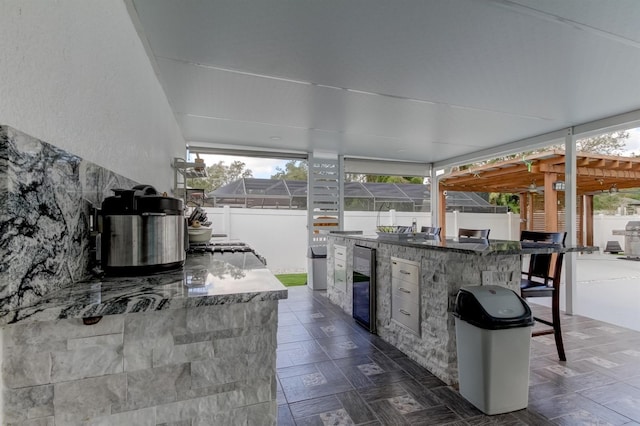view of patio with area for grilling, a fenced backyard, beverage cooler, and outdoor wet bar
