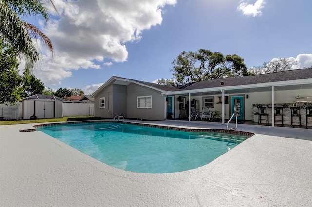 view of pool featuring a storage shed, a patio area, fence, a fenced in pool, and an outdoor structure