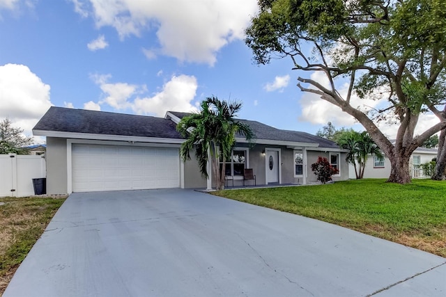ranch-style house featuring a front yard, fence, concrete driveway, an attached garage, and stucco siding